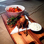 Photo: Lamb kofta sticks with a tomato salad and white bean soup, and rosemary presented on a wooden board.
